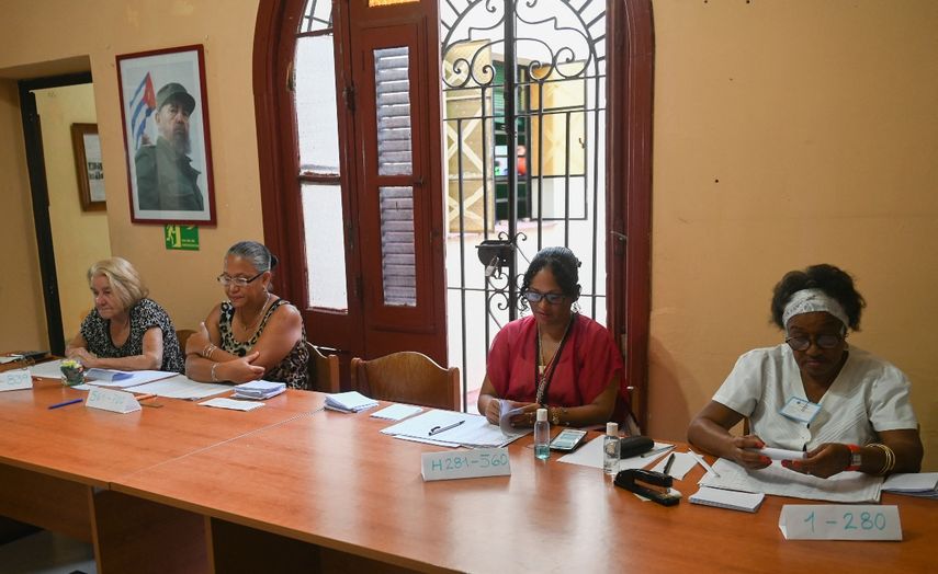Integrantes de un colegio electoral esperan a los electores durante la primera vuelta de las elecciones municipales para concejales convocadas por la dictadura de Cuba, en La Habana el 27 de noviembre de 2022.