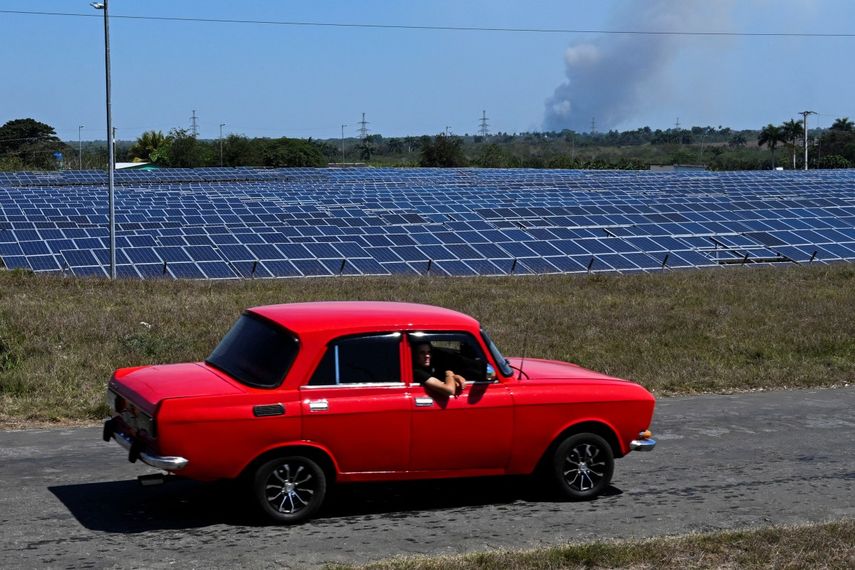 Un automóvil de la era soviética pasa junto a un parque fotovoltaico en Cienfuegos, Cuba, el 20 de marzo de 2025. No muy lejos de las ruinas de una central nuclear inacabada en la provincia cubana de Cienfuegos, cientos de trabajadores instalan apresuradamente 44.000 paneles solares mientras la isla busca reducir una vez más su dependencia del petróleo para escapar de una crisis energética.