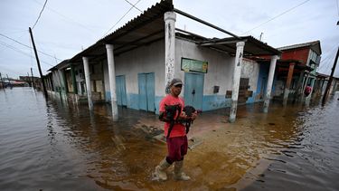 Un hombre lleva un perro mientras camina por una calle inundada tras el paso del huracán Rafel en Batabano, provincia de Mayabeque, Cuba, el 7 de noviembre de 2024.