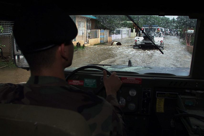 Fotografía de archivo de un oficial de la Guardia Nacional de Puerto Rico cruzando una calle inundada por fuertes lluvias.