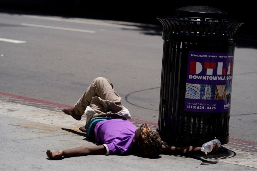 Un indigente yace sobre la acera con una botella de agua en la mano, el domingo 2 de julio de 2023, en el centro de Los Ángeles.&nbsp;