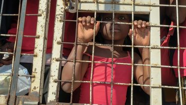 Un niño junto con personas detenidas para ser deportadas hacia Haití, en un camión policial, en un puente que conecta a Dajabón, República Dominicana, con Haití, el 18 de marzo de 2024. 