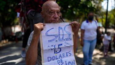 Carlos Blanco, de 84 años, supervisor de ambulancias retirado, sostiene un cartel que anuncia el pago mensual de su pensión de $1.50 dólares durante una protesta en que demandaban un incremento en los pagos en medio de una inflación récord en Caracas, Venezuela. 