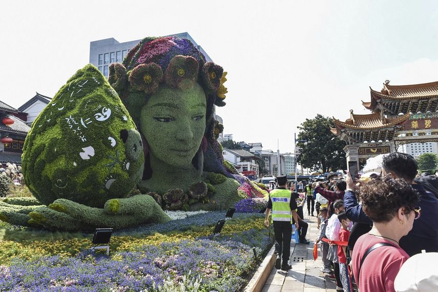 Turistas pasan junto a una decoración floral con motivo de la Conferencia de Biodiversidad de Naciones Unidas COP15 en un parque de Kunming, la ciudad anfitriona, en la provincia suroccidental china de Yunnan, el 2 de octubre de 2021.&nbsp;