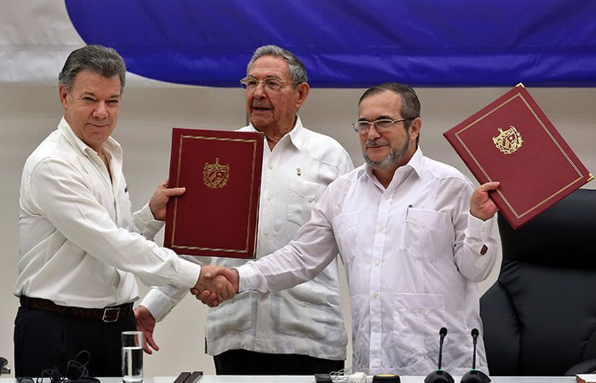 Rodrigo Londoño Echeverri, alias Timochenko (d) y Juan Manuel Santos (i) junto a Raúl Castro (c) sostienen en sus manos el acuerdo del final del conflicto armado entre el Gobierno colombiano y las FARC, durante la ceremonia en La Habana. La firma def