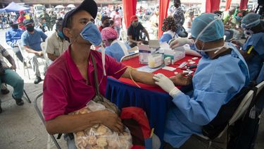 Un trabajador de salud le toma una muestra de sangre para una prueba rápida de COVID-19 a un hombre que trabaja vendiendo galletas en el mercado de alimentos de Coche en Caracas, Venezuela, el martes 23 de junio de 2020.