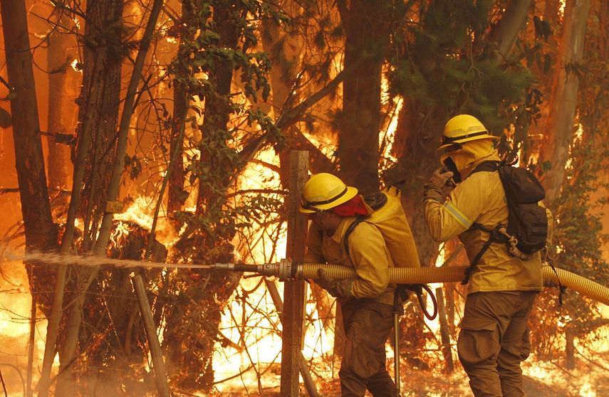 Dos bomberos tratan de apagar el fuego en la comuna de Cauquenes el pasado 24 de enero de 2017.&nbsp;
