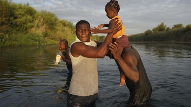 Hombres cargan a una niña a través del Río Bravo mientras los migrantes, muchos de Haití, abandonan Del Río, Texas, para regresar a Ciudad Acuña, México, el miércoles 22 de septiembre de 2021 temprano, algunos para evitar una posible deportación de EEUU otros a conseguir suministros