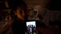 María Carla Milán Ramos muestra una foto en su teléfono de su esposo con sus hermanos, quienes están en prisión acusados de participar en protestas contra el régimen en julio del año pasado, en su casa del barrio La Güinera en La Habana, Cuba, el miércoles 19 de enero de 2022
