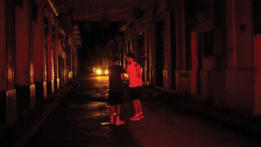 Dos jóvenes caminan por una calle de La Habana durante apagón de electricidad.