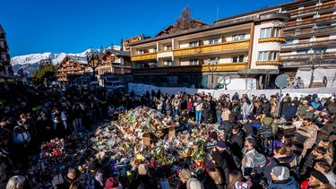 La gente se reúne alrededor de un monumento improvisado para presentar sus respetos depositando flores, velas y mensajes cerca del bar Constellation, el 4 de enero de 2026, en Crans-Montana, en honor a las víctimas del incendio que arrasó el local en la lujosa estación de esquí alpina la víspera de Año Nuevo. &nbsp;