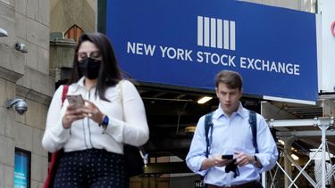 Dos jóvenes pasan cerca de un anuncio de Wall Street.