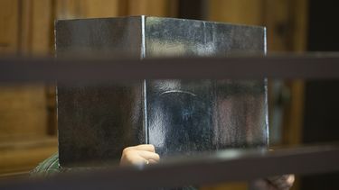 El acusado en un supuesto caso de canibalismo se cubre la cara con un cartón en la primera sesión de su juicio en Berlín, el 10 de agosto de 2021.&nbsp;