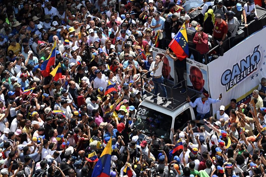 La líder de la oposición venezolana María Corina Machado (C), ondea una bandera nacional encima de un camión durante una protesta convocada por la oposición para que se reconozca la 
