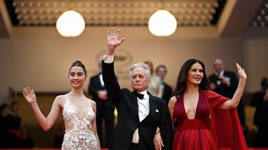 El actor estadounidense Michael Douglas saluda cuando llega con su esposa, la actriz británica Catherine Zeta-Jones y su hija Carys para la ceremonia de apertura y la proyección de la película Jeanne du Barry durante la 76ª edición del Festival de Cine de Cannes, en donde recibirá la Palma de Oro Honoraria.