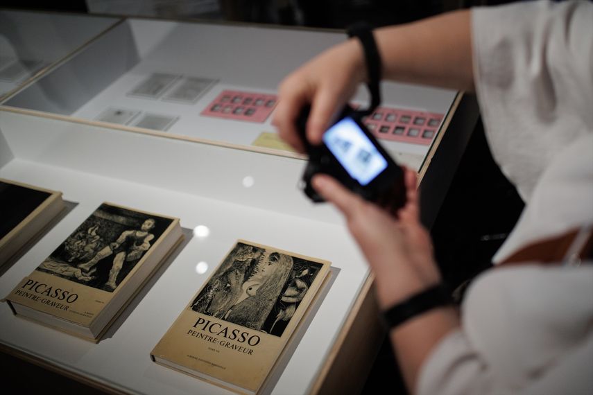 Una mujer fotografía uno de los libros que componen la exposición Picasso en foto. Archivos del Museu Picasso de Barcelona, en el Fernán Gómez Centro Cultural de la Villa el 28 de abril de 2023, en Madrid (España). 