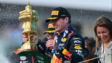 El piloto holandés de Red Bull Racing, Max Verstappen, que sostiene el trofeo, reacciona cuando el segundo clasificado, el piloto británico de McLaren, Lando Norris, rocía champán durante la ceremonia del podio del Gran Premio de Gran Bretaña de Fórmula Uno en el circuito de carreras de Silverstone, en el centro de Inglaterra, el 9 de julio de 2023. &nbsp;