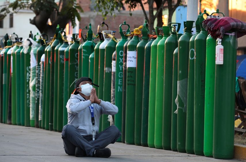 Alejandro Ccasa reza después de esperar días junto a un tanque de oxígeno vacío para su tío que tiene COVID-19 afuera de una tienda de recarga donde es el primero en Callao, Perú, la madrugada del martes 2 de febrero de 2021