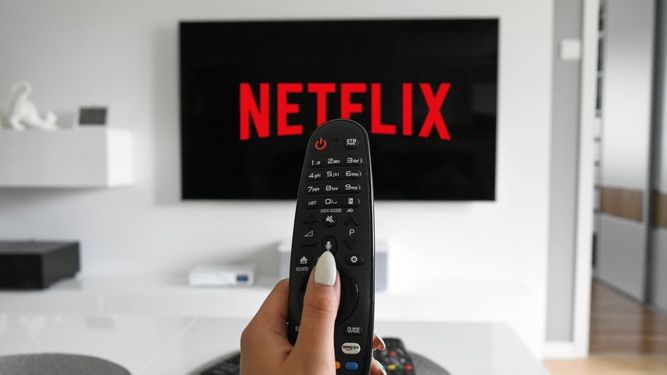 Una persona con un control de televisión entra en la plataforma de Netflix.