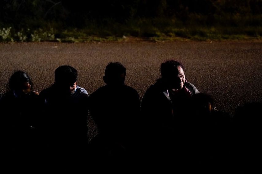 Un grupo de migrantes esperan en una carretera tras entregarse a las autoridades luego de cruzar la frontera entre México y Estados Unidos, en La Joya, Texas.