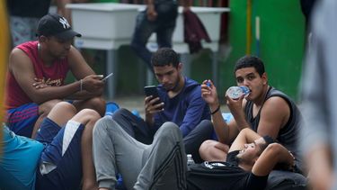 Migrantes venezolanos revisan sus teléfonos móviles mientras esperan en un albergue temporal, el martes 25 de octubre de 2022.