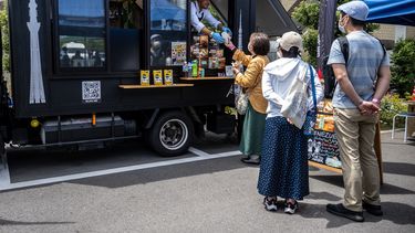 El venezolano Raúl Márquez (centro) vende arepas, un popular platillo sudamericano hecho con harina de maíz, desde su camión de comida durante un evento en un mercado de agricultores en Ichikawa, prefectura de Chiba, un suburbio al este de Tokio, el 27 de mayo de 2023. De Caracas a Nueva York, pasando por París, Tokio y Hong Kong, en puestos callejeros y restaurantes gourmet... La arepa, plato venezolano a base de maíz, conquista el mundo gracias a una ola migratoria y al creciente mercado sin gluten . &nbsp; Felipe FONG / AFP