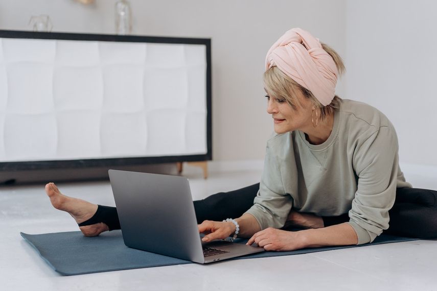 Una mujer realiza ejercicios mientras mira su laptop.&nbsp;