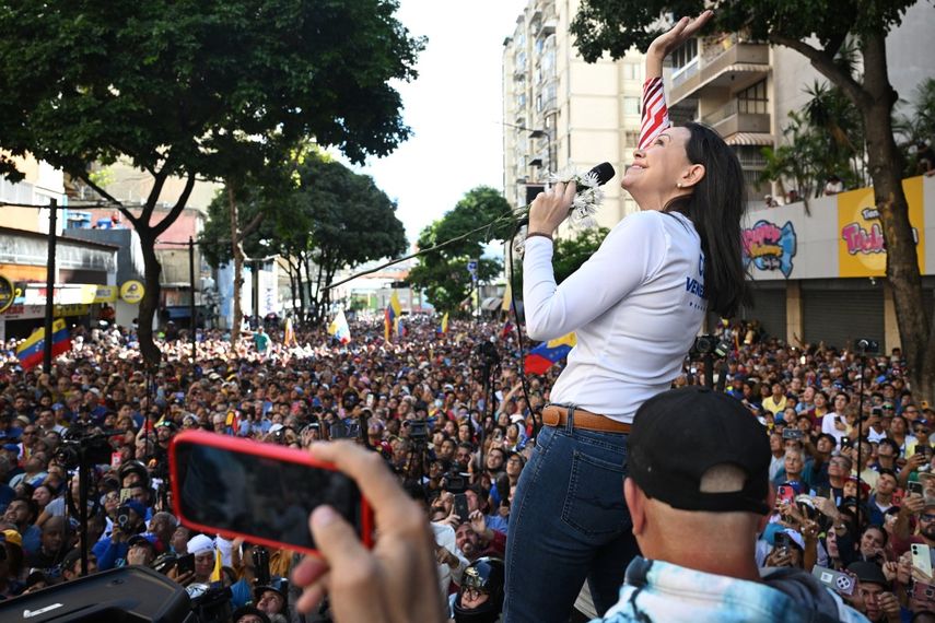 La líder de la oposición, María Corina MAchado, saluda a un avión del régimen que sobrevolaba por la manifestación opositora en Caracas