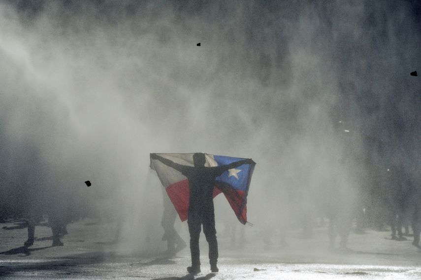 ARCHIVO - En esta imagen de archivo del 25 de octubre de 2019, un manifestante contrario al gobierno sostiene una bandera chilena en choques con la polic&iacute;a en Valpara&iacute;so, Chile.&nbsp;