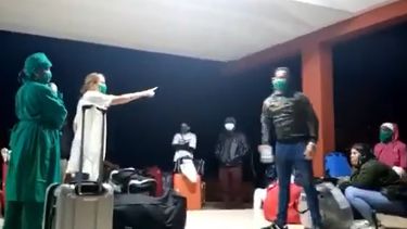 Una aparente enfermera levanta su mano en direcci&oacute;n a una de las personas confinadas como prevenci&oacute;n frente al coronavirus en una escuela en La Habana.
