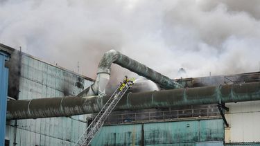 Un bombero lanza agua para sofocar las llamas en la planta de Covanta en Doral.