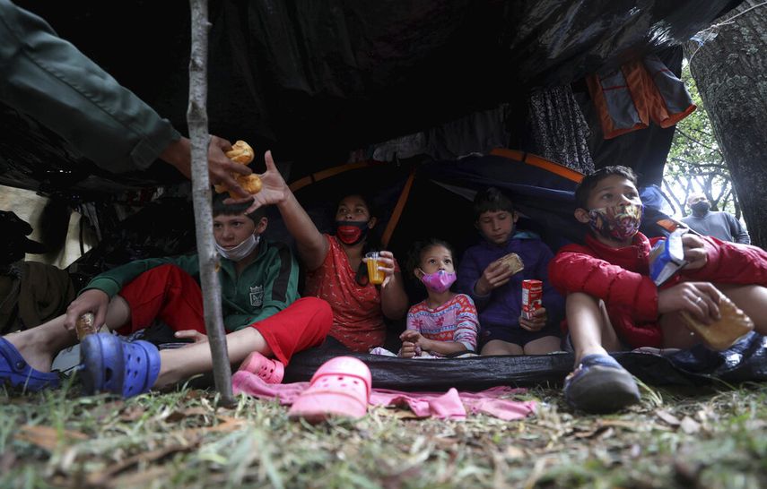 Una familia de migrantes venezolanos desayuna en un campamento cerca de la terminal principal de autobuses en Bogotá, Colombia.