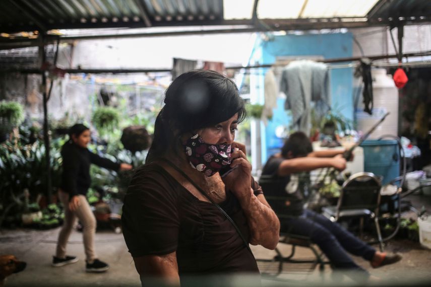 Elisa Xolalpa, quien cuando tenía 18 años sobrevivió a un ataque con ácido mientras estaba atada a un poste por su expareja hace 20 años, habla por celular mientras sus hijos juegan en la casa de sus padres en la Ciudad de México, el domingo 4 de julio de 2021. Xolapa dijo que nadie puede permitir que se normalice la violencia y que ese es un mensaje que quiere enseñar a sus hijas.