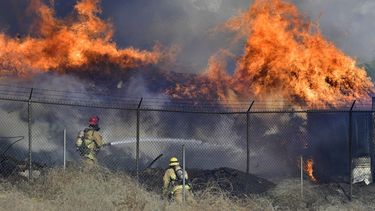 Dos bomberos combaten un incendio que arde fuera de control el jueves 3 de diciembre de 2020, en Riverside, California.&nbsp;