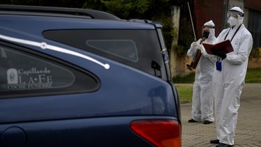 Un empleado de una funeraria toca el viol&iacute;n mientras un di&aacute;cono reza durante el acompa&ntilde;amiento de luto antes de la cremaci&oacute;n de una v&iacute;ctima del nuevo coronavirus COVID-19, en el cementerio Seraf&iacute;n de Bogot&aacute;, el 17 de julio de 2020