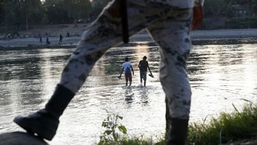 En esta fotografía del 22 de enero de 2020, unos migrantes hondureños que trataron de cruzar la frontera hacia México a pie regresan al lado guatemalteco del río Suchiate bajo la vigilancia de un elemento de la Guardia Nacional mexicana, cerca de Ciudad Hidalgo, México.