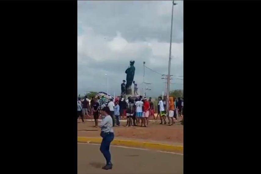 Turba de personas derribando una estatua del fallecido presidente venezolano Hugo Chávez.