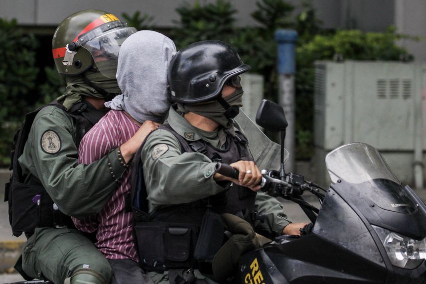 La Guardia Nacional Bolivariana (GNB) se lleva a un manifestante opositor durante una protesta.
