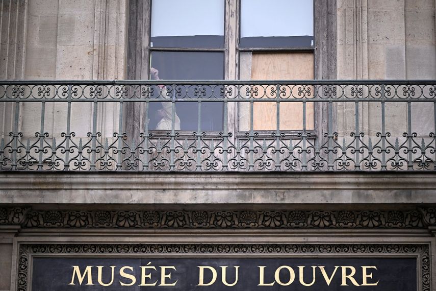Una persona se encuentra detrás de la ventana por donde entraron los ladrones que robaron ocho valiosas joyas reales del Museo del Louvre, en París, el 20 de octubre de 2025.