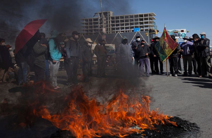 Manifestantes con tapabocas por el nuevo coronavirus queman un neumático durante una protesta contra el aplazamiento de las próximas elecciones presidenciales en El Alto, Bolivia. La máxima autoridad electoral de Bolivia retrasó las elecciones presidenciales&nbsp;por la pandemia.