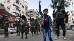 Un niño hace la señal de victoria frente a milicianos de Hamás.