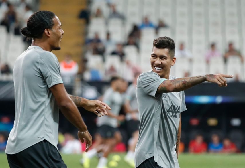 Los jugadores de Liverpool Roberto Firmino, derecha, y Virgil van Dijk sonríen durante una sesión de entrenamientos en el estadio de Besitkas, en Estambul, Turquía, el martes, 13 de agosto de 2019.