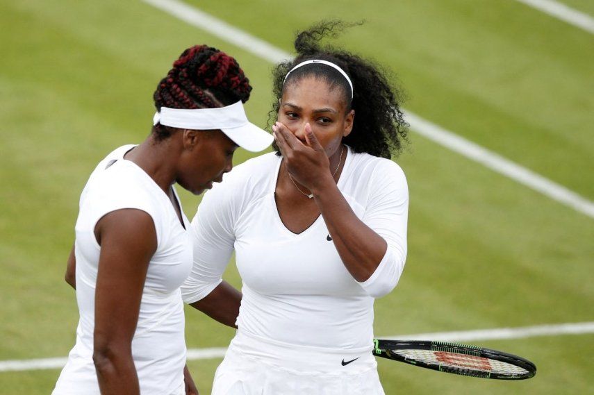 Las jugadoras estadounidenses Venus (izq) y Serena Williams hablan durante un partido de dobles en Wimbledon, el 30 de junio de 2016.