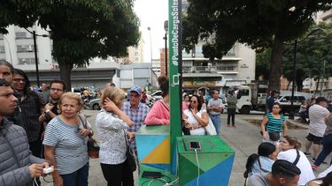 Varias personas hacen fila para recargar las baterías de sus teléfonos móviles en un punto público durante el apagón eléctrico en Caracas, Venezuela.