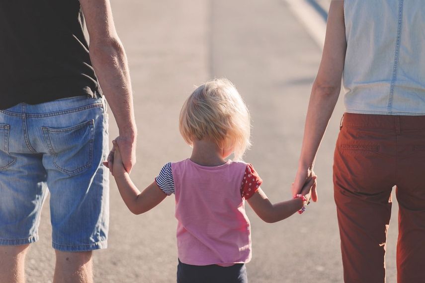 Pareja caminando con su hija por el parque.