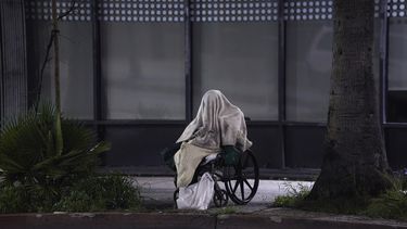 Una persona desamparada est&aacute; sentada en una silla de ruedas bajo la lluvia en Sunset Blvd., en el barrio de Echo Park en Los &Aacute;ngeles el 6 de abril del 2020. Para contener la diseminaci&oacute;n del coronavirus, Los &Aacute;ngeles est&aacute; enfrascada en una operaci&oacute;n masiva para sacar de las calles a miles de desamparados y llevarlos a hoteles para protegerlos y a otros de infecci&oacute;n.&nbsp;