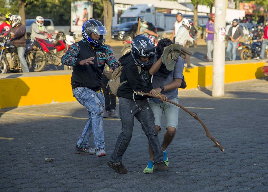 Dos miembros de las fuerzas antichoque agreden a una persona durante las protestas en contra de las reformas del Instituto Nicaragüense de Seguridad Social (INSS), en Managua (Nicaragua).&nbsp;