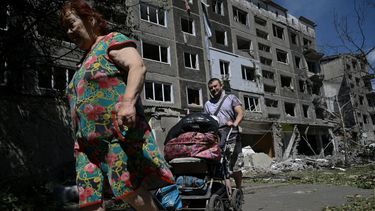 Foto de ucranianos frente a un edificio bombardeado por los rusos en la region del Donetsk.
