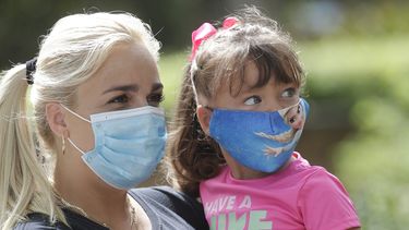 Madre e hija usan mascarillas al entrar al zoológico de Miami.
