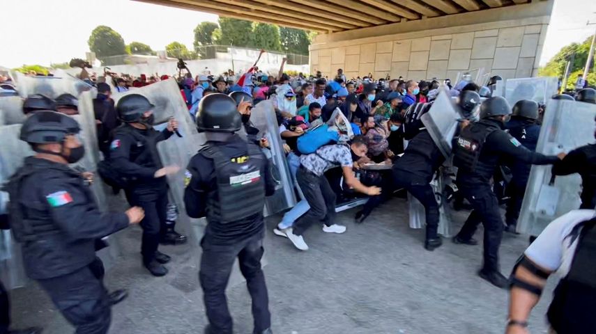 Una caravana de migrantes, la mayoría de Centroamérica, atraviesa por la fuerza una barricada de la policía mexicana en Tapachula, México, el sábado 23 de octubre de 2021.